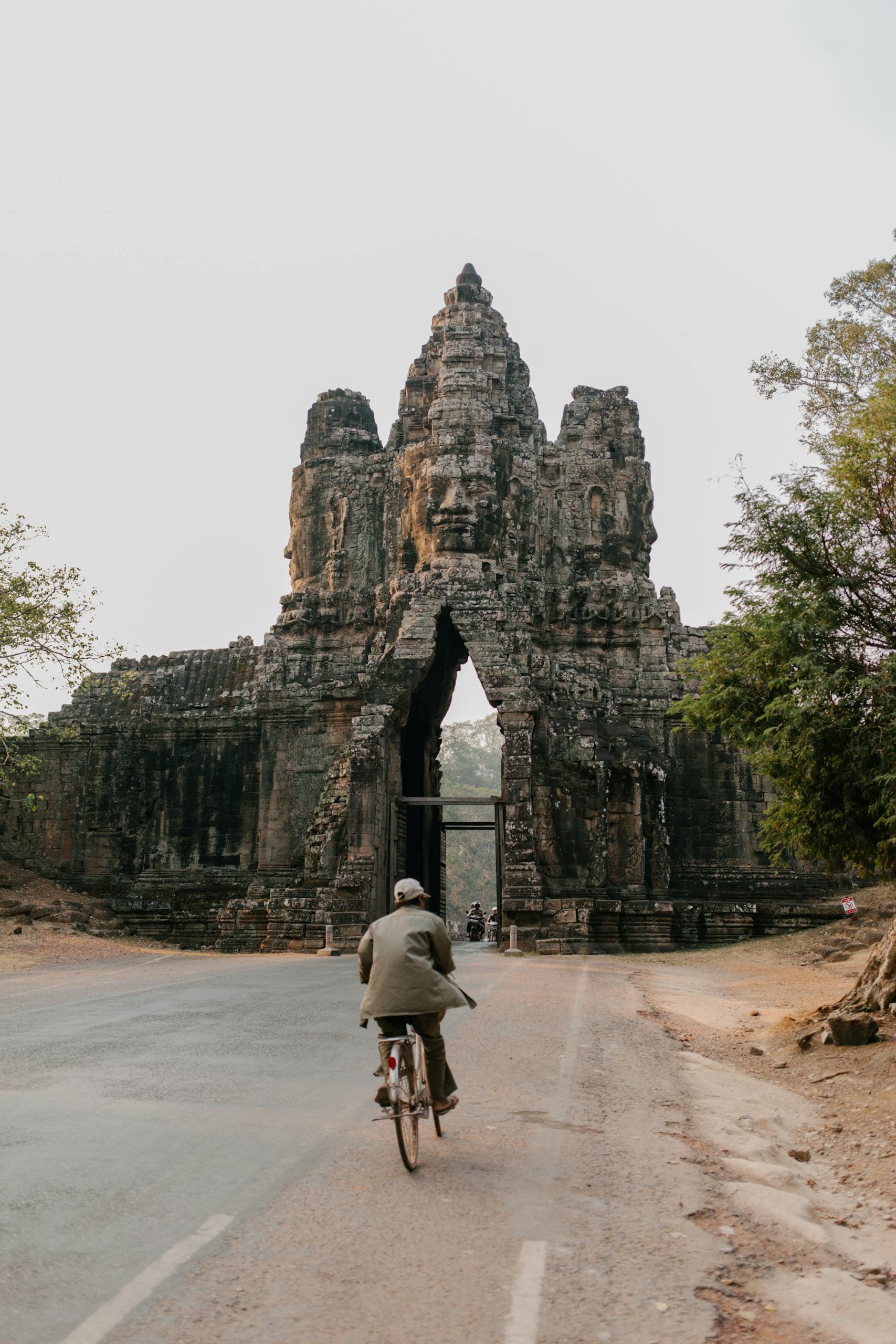 A cyclist rides a bicycle through the iconic South Gate of Angkor Thom in Cambodia.