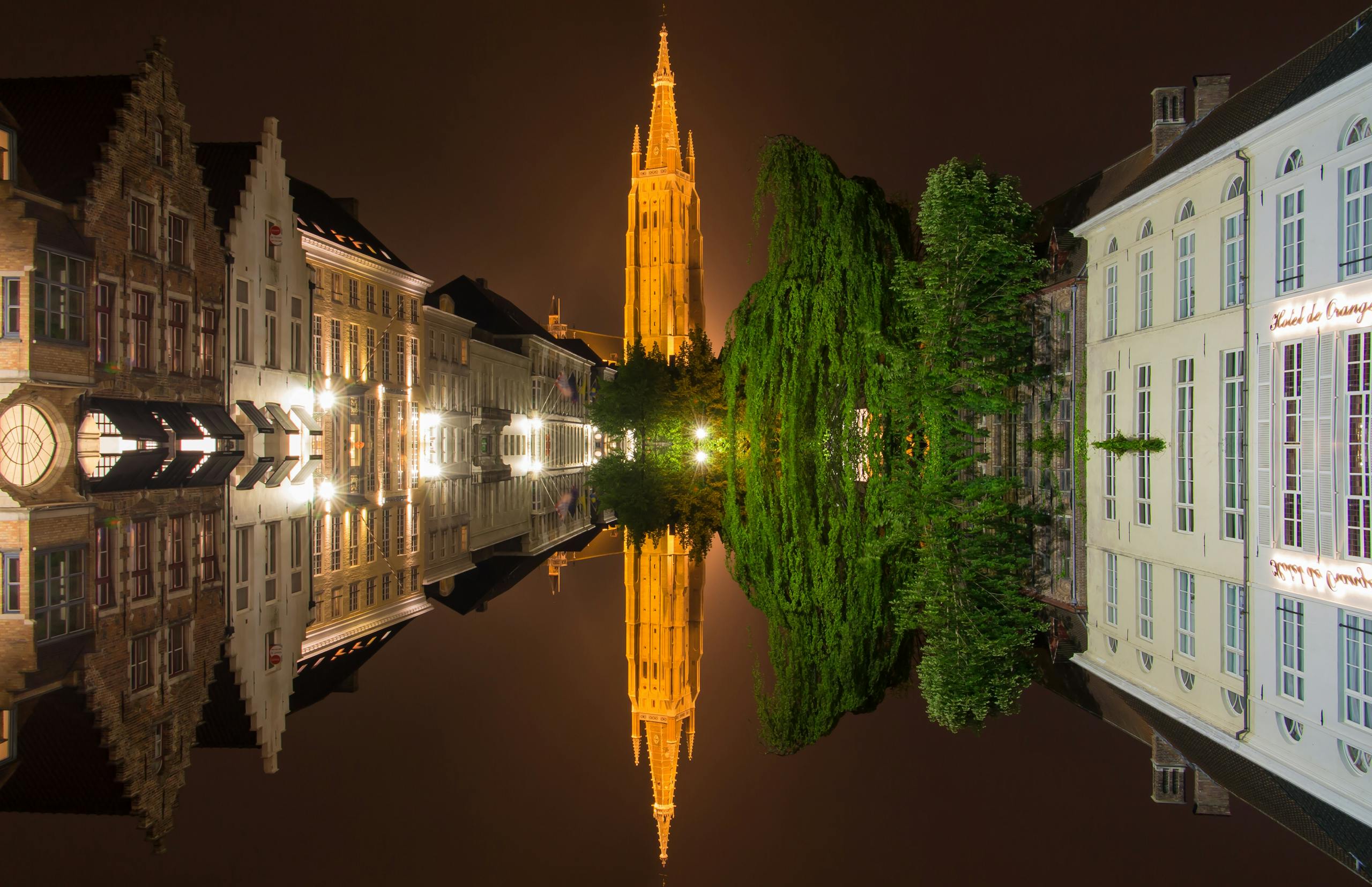 Stunning view of Bruges with illuminated reflections on the water at night, showcasing historic architecture.