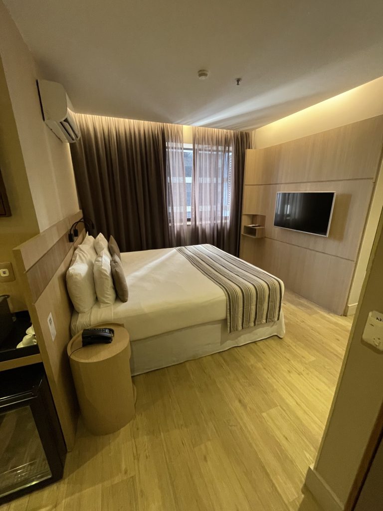 clean hotel room with tv, bed, and light colored lvp floors