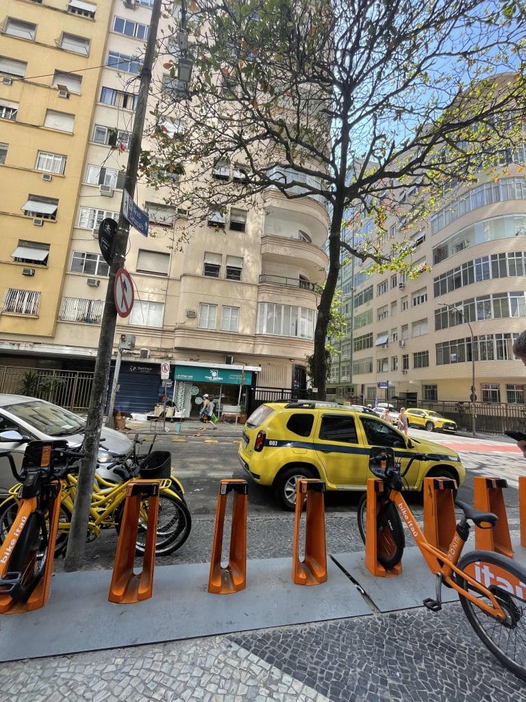 yellow taxi and orange rental bikes on road in Rio de Janeiro
