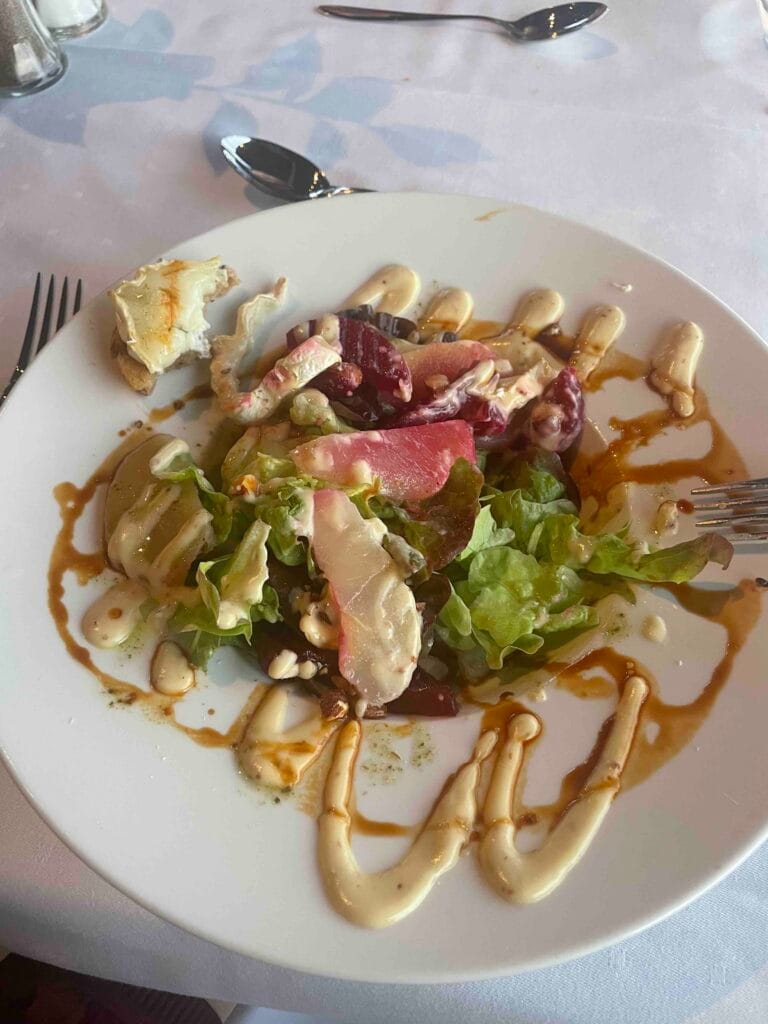 Salad with pear and beet, dressing drizzled over plate
