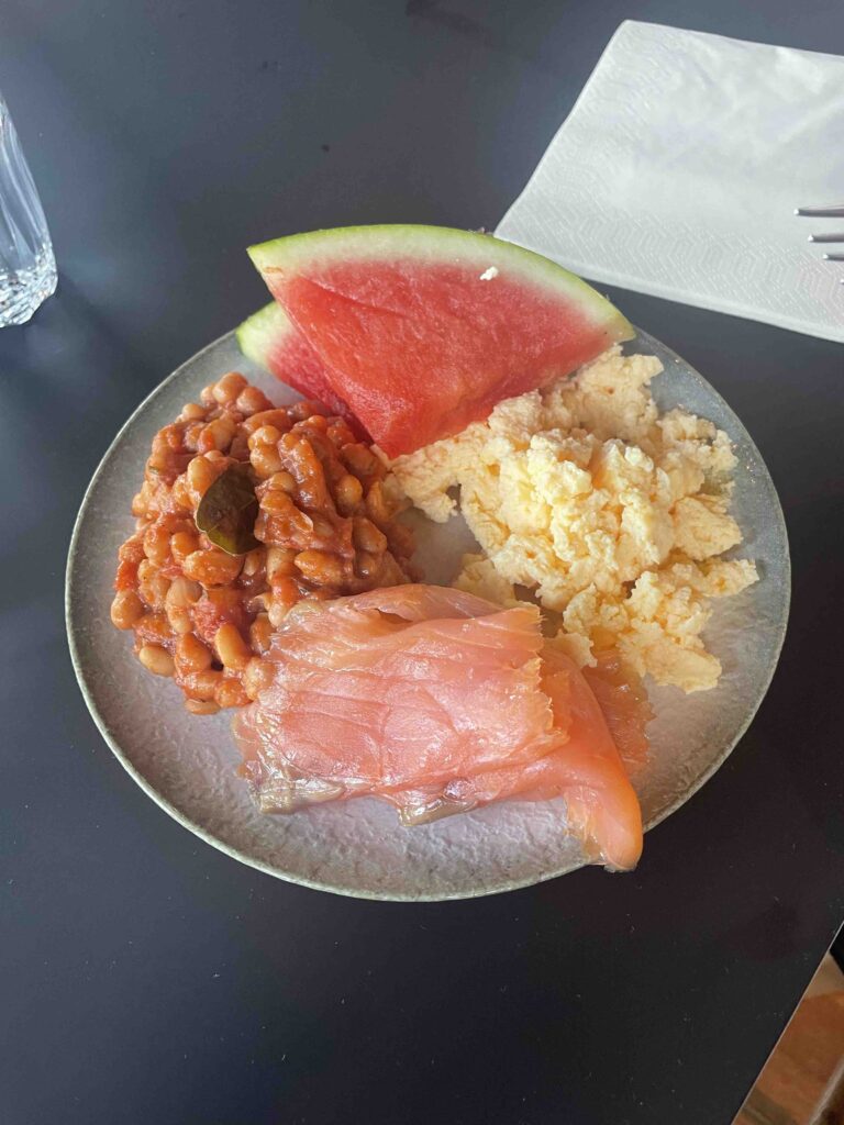 Hotel breakfast with baked beans, watermelon, eggs, and salmon