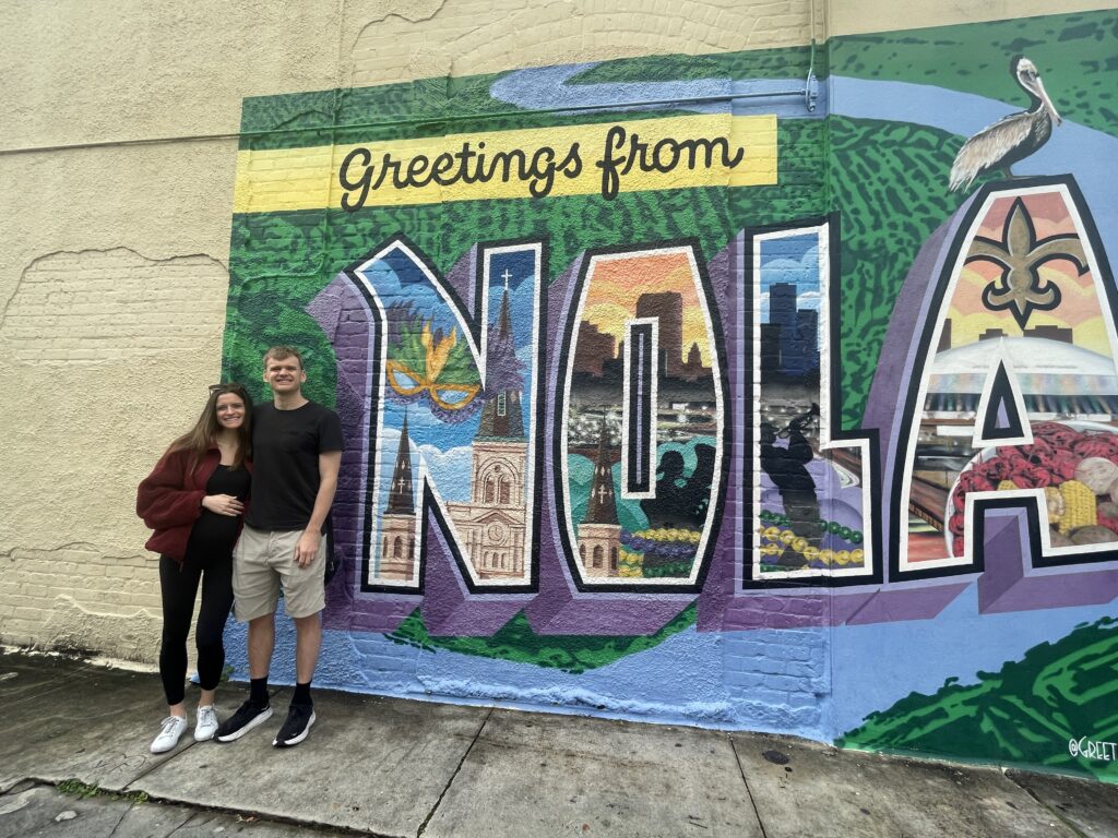 man and woman in front of NOLA mural in New Orleans